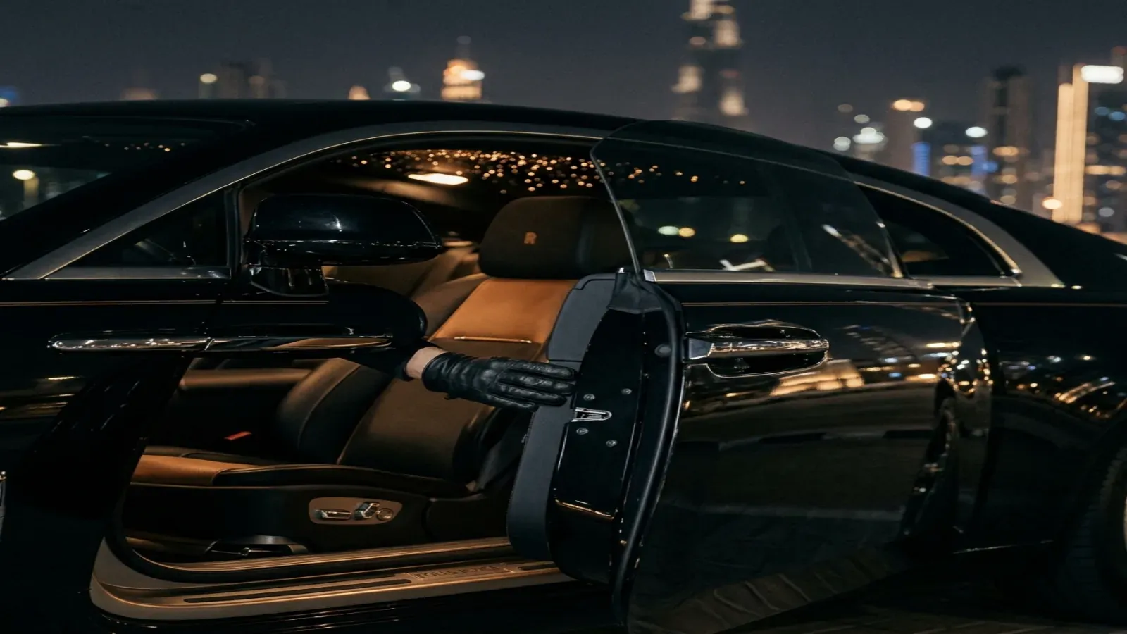 A sinister black-on-black Rolls-Royce Wraith coupe parked in front of a modern glass skyscraper in Downtown Dubai