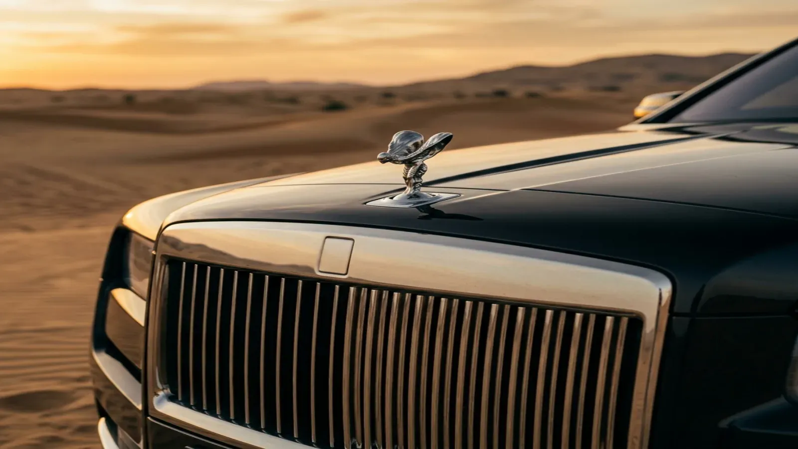 Pearl-white Rolls-Royce Cullinan at the Dubai desert edge at dusk.