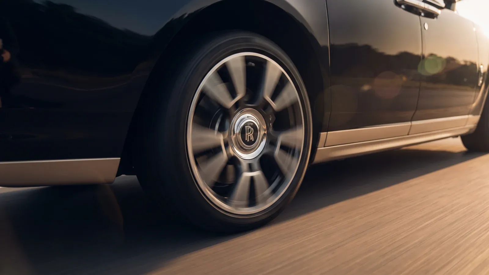A Rolls-Royce Ghost accelerating smoothly on a Dubai highway at sunset.