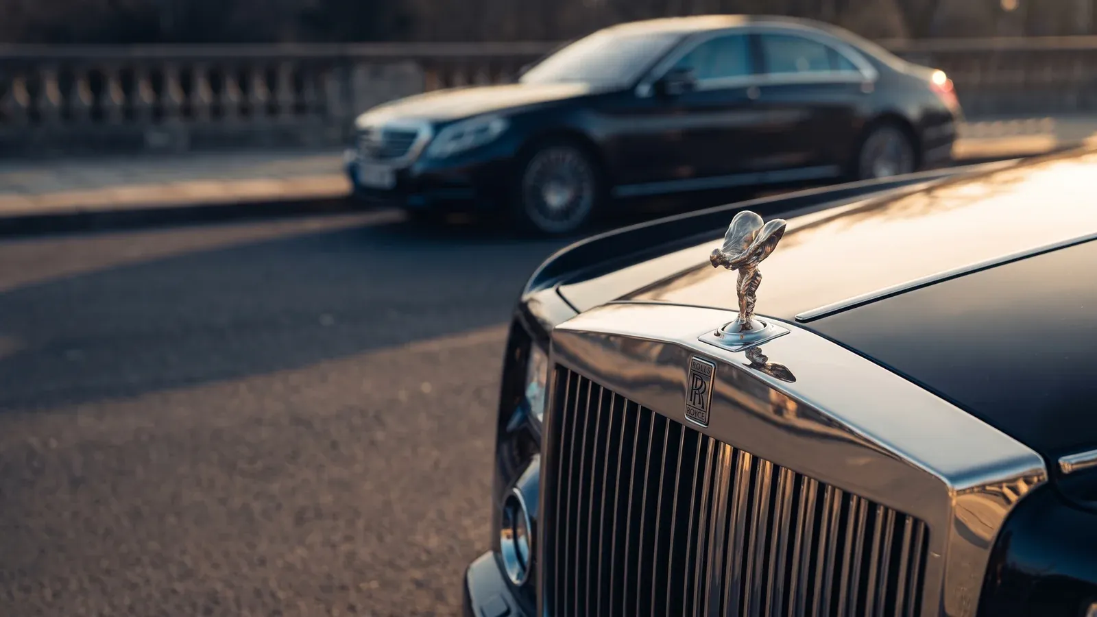 A Rolls-Royce Ghost and a Bentley Flying Spur parked side-by-side in front of a luxury Dubai hotel