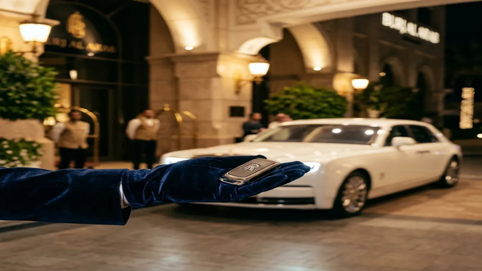 Потрясающий черный Rolls-Royce Phantom, припаркованный перед роскошным курортом Дубая на закате.