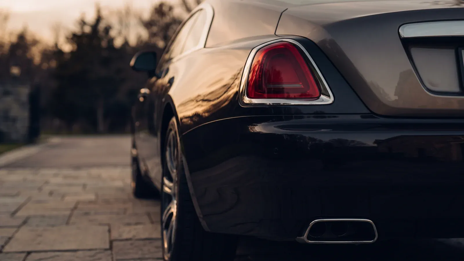 A Rolls-Royce Spectre accelerating silently on a scenic road in Dubai at sunset