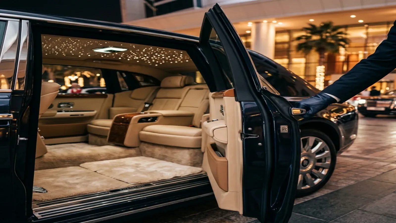 Chauffeur opens a Rolls-Royce Phantom door at a Dubai hotel at blue hour.